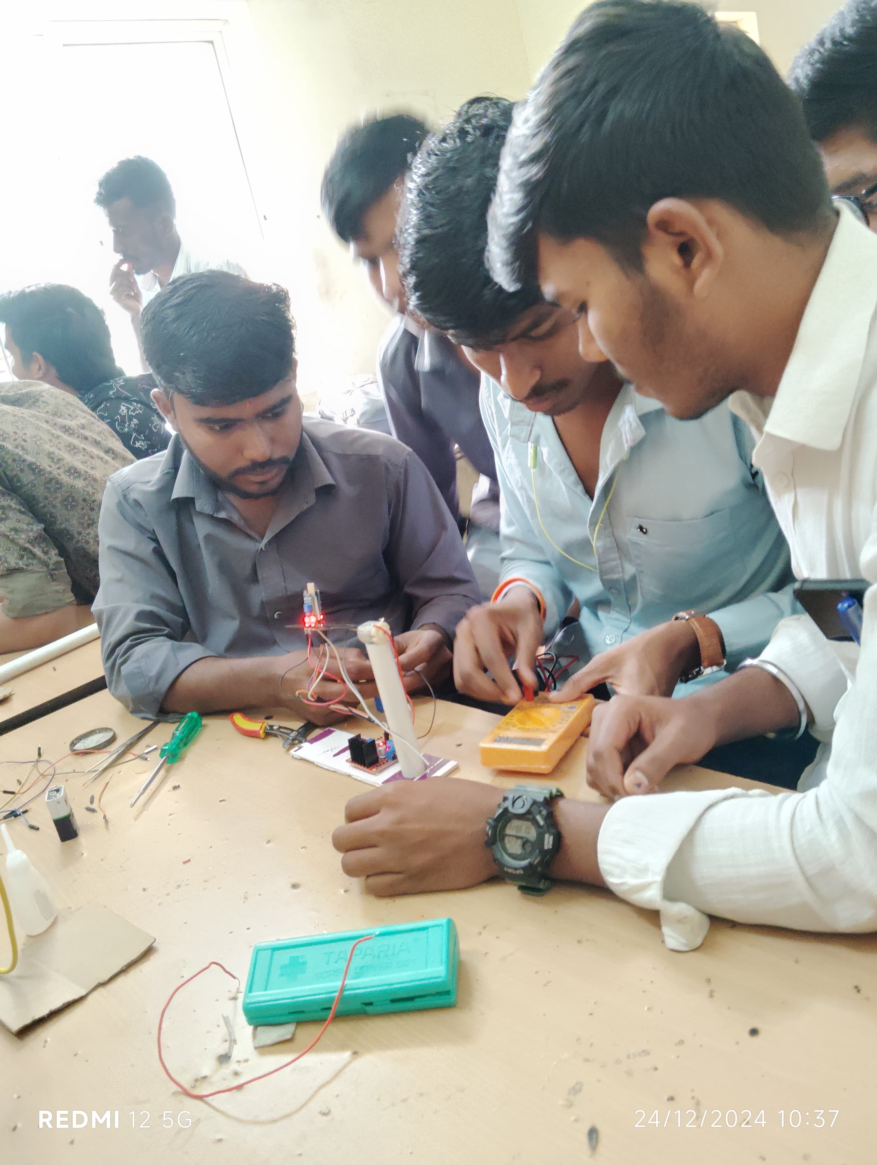 Trainees testing a circuit board with a multimeter